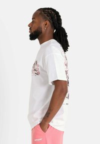 Wit katoenen T-shirt met een grafische print op de voorkant, een ronde hals en korte mouwen, gecombineerd met roze korte broek.