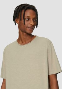 Lichtbeige T-shirt met korte mouwen, gemaakt van zacht materiaal, met een ronde halslijn en een relaxte pasvorm. Het heeft een gladde textuur en een minimalistisch ontwerp.