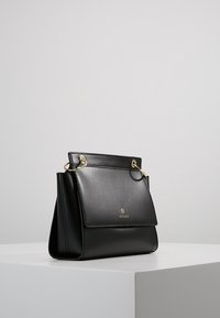 Czarna skórzana torebka o wyraźnie zarysowanym kształcie, z przednią klapką, złotymi elementami i bocznymi pierścieniami. Gładka tekstura i wypukłe logo.