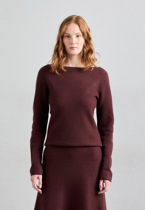 Burgunderullstrikket genser med lange ermer og bred båtkrage, kombinert med et matchende tettsittende skjørt. Myk tekstur og minimale designelementer.