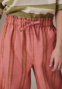 Roze gestreepte broek met een textuurstof, voorzien van een ontspannen tailleband en een strik. Verticale strepen bevatten tinten oranje en geel.