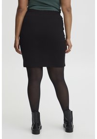 Zwarte, knielange pencil skirt met een elastische tailleband, gecombineerd met zwarte panty’s en enkellaarsjes. Glad materiaal, slim fit ontwerp.