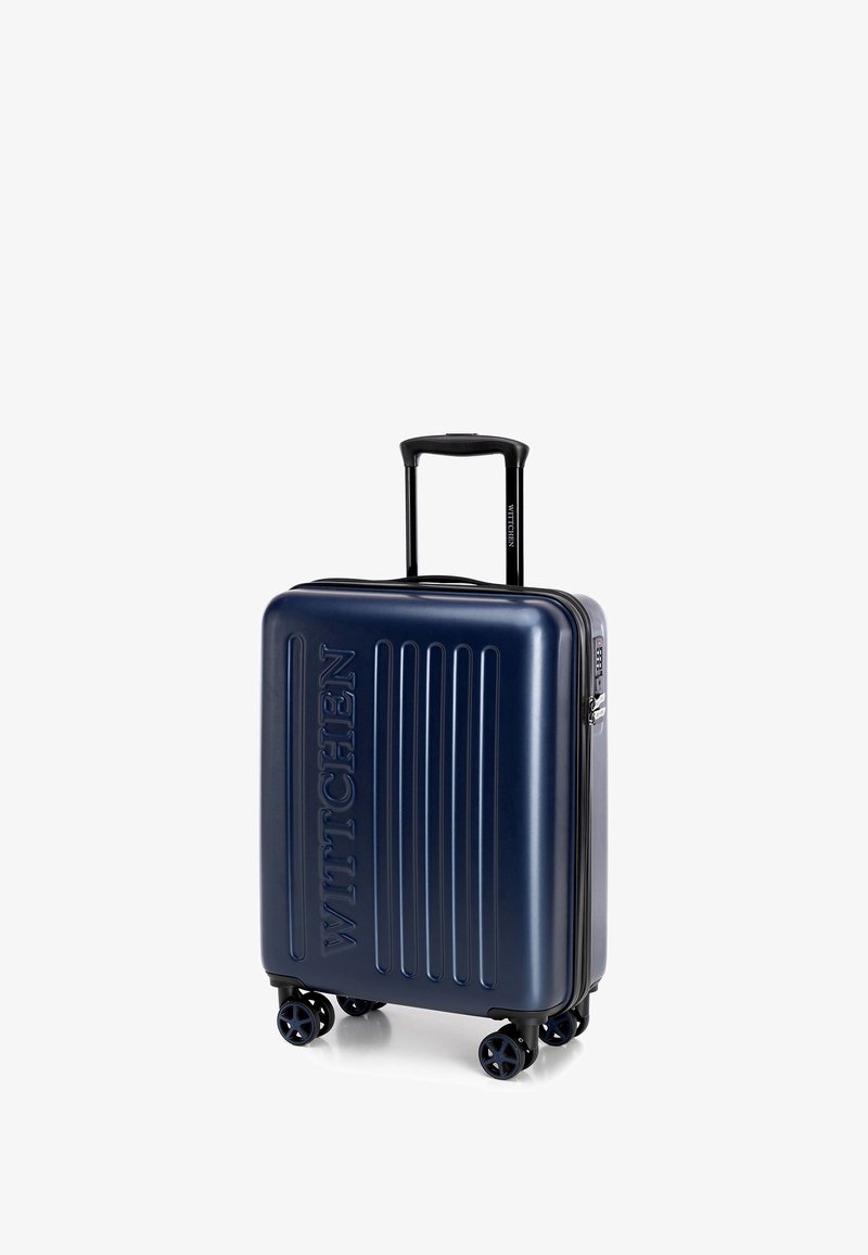 Maleta rígida de color azul marino con surcos verticales, logo grabado "WITTCHEN", mango retráctil, cuatro ruedas y cierre de cremallera.