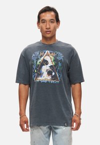 Grafisk t-shirt i mörkgrå bomull med en färgglad tryck av en hund inom en triangel, med djärva detaljer och avslappnad passform.