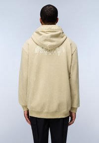 Sudadera con capucha beige de textura suave, que presenta un estampado gráfico en la parte posterior de árboles y texto, puños acanalados y un dobladillo en la cintura.