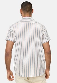 Chemise à manches courtes avec une base blanche, présentant des rayures verticales bleues et oranges. Fabriquée en tissu léger avec une coupe décontractée.