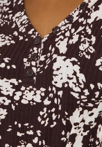 Kurzarm-BUTTON-UP-Oberteil aus dunklem burgunderfarbenem, geripptem Stoff mit weißen Blumenmustern, ausgestattet mit vier schwarzen Knöpfen am Ausschnitt.