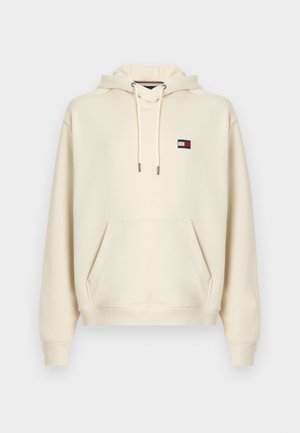 Φούτερ με κουκούλα μπεζ χρώματος από μαλακό ύφασμα, με τσεπάκι μπροστά, κουκούλα με κορδόνι και μικρό κεντητό λογότυπο σε μπλε, κόκκινο και άσπρο χρώμα.