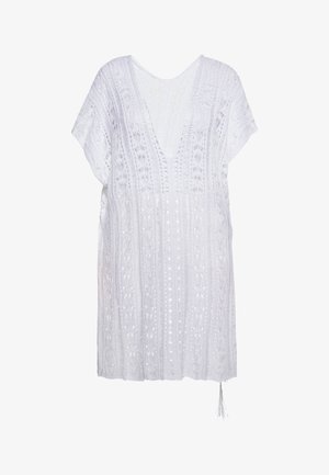 Balta tunika ar V veida kaklu, īsām piedurknēm, sarežģītu tamborējuma tekstūru un dekoratīvām rakstāmzīmēm visā virsmā. Iekļauts pompoņi akcentam.