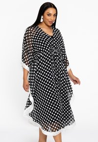 Schwarzes Polka-Dot-Kaftan aus transparentem Stoff, mit einem Kordelzug in der Taille, weißen Akzenten und ausladenden Ärmeln. Entworfen für eine fließende Silhouette.