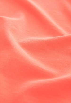 Materiał w kolorze koralowym o miękkiej, gładkiej fakturze i delikatnej elastyczności, przedstawiający łagodne fale i zagięcia typowe dla lekkiej bawełny.