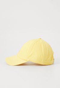 Gul baseballcap med buet skygge og justerbar stropp, vist på en hvit overflate i sidevisning.
