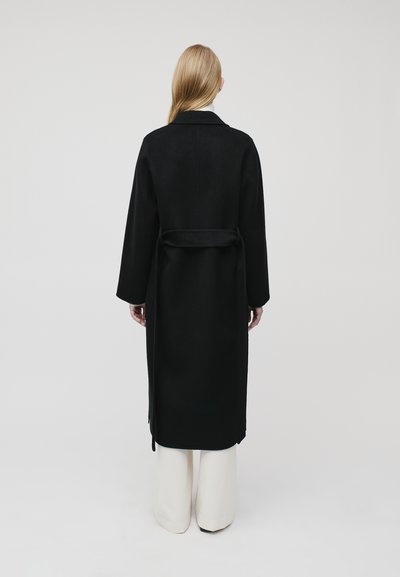 Black wool coat with long sleeves, a tie waist, and a minimalist design. Smooth texture, knee-length, displayed from the back.