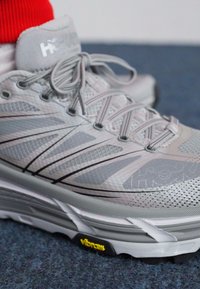 Hallitusroheline jooksutoss, millel on võrgust ülemine osa, mustad aktsendid ja Vibram tald. Omab silmapaistvat nöörimissüsteemi ja logo keelel.