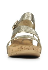Sandales compensées dorées métalliques avec deux larges sangles et une boucle circulaire, dotées d'un semelle en liège et d'une surface supérieure texturée.