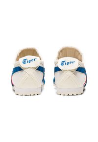 Witte canvas schoenen met blauwe accenten, voorzien van een ronde neus, gestructureerde zool en het kenmerkende "Tiger" logo op de hak. Zichtbare stiksel detail.