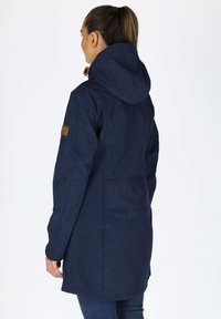Navy blue long coat with a hood, featuring a textured fabric, side pockets, and a brown leather accent on the sleeve.