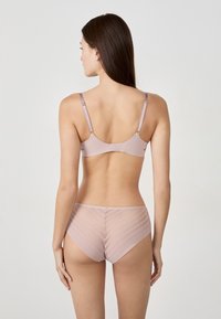 Ensemble de lingerie rose clair comprenant un soutien-gorge et une culotte, avec une texture lisse et brillante. Le soutien-gorge a des bretelles réglables ; la culotte présente des rayures horizontales transparentes.