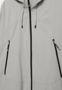Světlounce šedá bunda s kapucí, černým zipem a zipovanými kapsami, s nastavitelnými šňůrkami na kapuci.