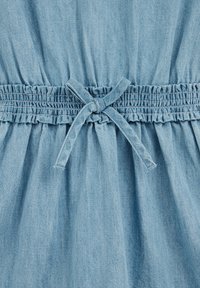 Svetlo modra denim obleka z nabranim pasom, detajlom v obliki mašne spredaj in teksturirano tkanino z nabranim krilom.