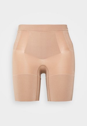 Shorts de compression couleur chair fabriqués dans un matériau élastique, avec une texture lisse, un design ajusté et sans coutures visibles pour un look épuré.