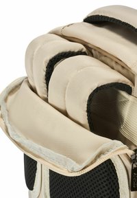 Beżowa torba z materiału z wyś cushioning, czarnymi akcentami z siateczki i zapięciem na zamek. Posiada zaokrąglone krawędzie oraz teksturowaną powierzchnię dla lepszego chwytu.