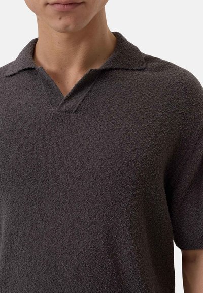 Polo shirt grigio scuro con un tessuto testurizzato e peloso, caratterizzato da un colletto classico e un design a V, maniche corte e vestibilità casual.