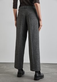 Grå, texturerade, högmidjade byxor med vida ben och bakfickor; matchat med svarta ankelskor.