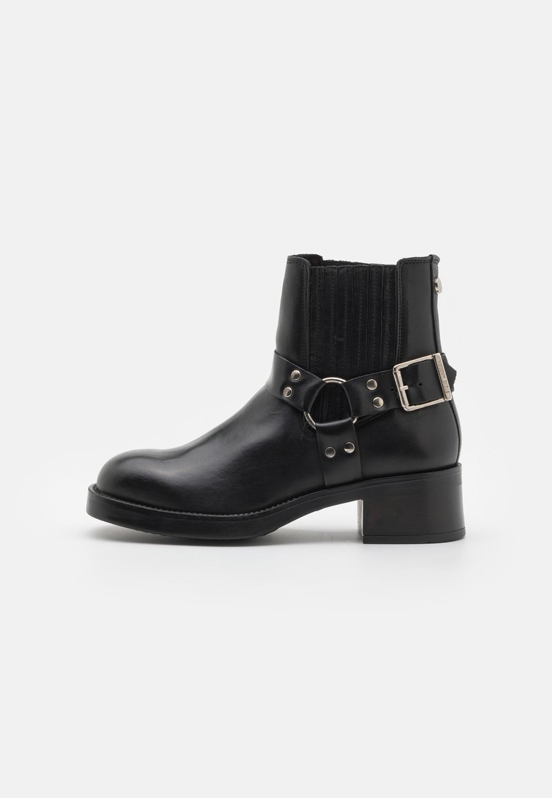 Black leather ankle boot with a rounded toe, elastic side panels, decorative strap with metal hardware, and a low block heel.