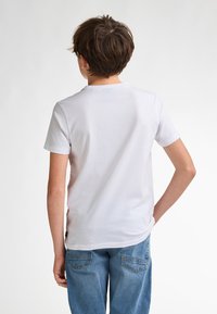 Hvid bomulds T-shirt med rund hals og korte ærmer, enkel design med en blød tekstur, parret med lyseblå jeans.