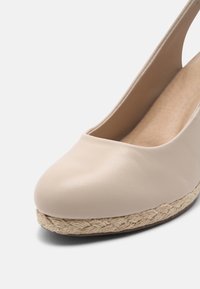 Scarpa con zeppa in pelle beige, con punta arrotondata, piattaforma in juta stile espadrilles e una superficie liscia sulla parte superiore.