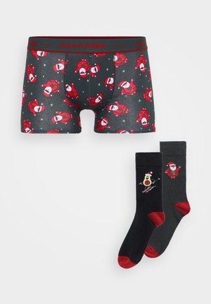Boxershorts aus dunklem Stoff mit rotem Weihnachtsmann-Motiv, kombiniert mit schwarzen Socken mit roten Akzenten und einem Skifahrenden Weihnachtsmann-Design.