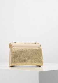 Borsa in paglia intrecciata dorata con parte superiore in pelle beige liscia, forma rettangolare, tracolla a catena e chiusura con zip.