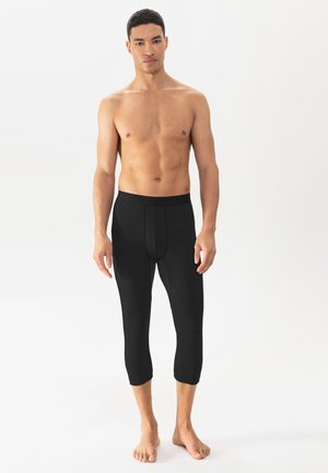 Zwarte, aansluitende leggings met een gestructureerde afwerking en een band rond de taille, die tot halverwege de kuit reikt. Ontworpen voor comfort en bewegingsgemak.