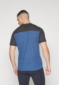 Blue and black short-sleeve athletic shirt with a color-blocked design, textured fabric, and rounded hem. Suitable for active wear.