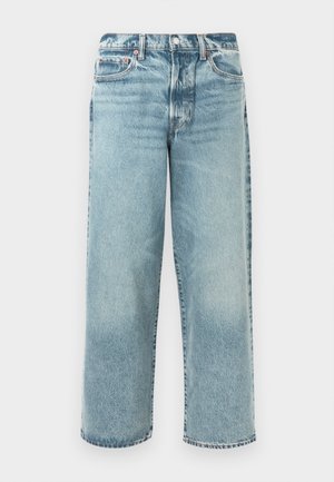 Vaaleat pesetyt farkut, joissa on rento leikkaus, suora lahje, puolimatalat vyötärö, viisi taskua ja näkyvät ompelutiedot.