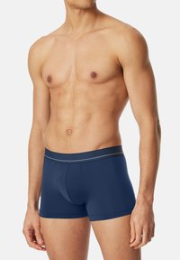 Boxer in blu navy realizzati in tessuto morbido, dotati di una fascia elastica liscia con il nome del marchio e un sottile dettaglio a striscia in contrasto.