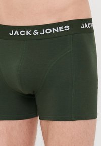 Grüne Baumwoll-Boxershorts mit einem weißen elastischen Bund, der den Text "JACK & JONES" zeigt, enganliegendem Schnitt und verstärkten Nähte an den Säumen.