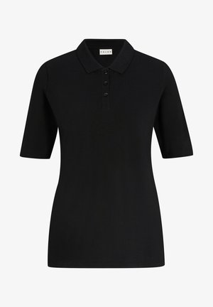 Zwarte poloshirt met korte mouwen, een kraag en drie knopen, gecombineerd met beige tapse broeken en zwarte instappers. Eenvoudig en strak ontwerp.