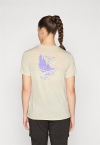 Light beige short-sleeve t-shirt made of soft fabric, featuring a purple nature scene graphic on the back with trees and mountains.