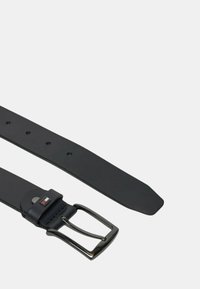 Cintura nera in pelle con una texture liscia, dotata di una fibbia in metallo argentato e di uno spuntone rettangolare. Include fori per la regolazione della misura.