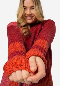 Strickpullover mit einem Farbverlauf aus Rot- und Orangetönen und gerippter Textur. Überdimensionierte Ärmel mit gerippten Bündchen sorgen für Wärme und Detail.