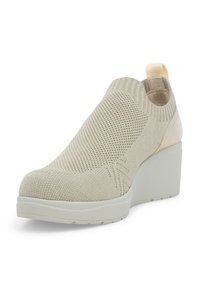 Scarpa slip-on lavorata a maglia beige con tomaia testurizzata, punta arrotondata e tacco a cuneo; presenta un'etichetta sul retro per facilitare l'indossamento.