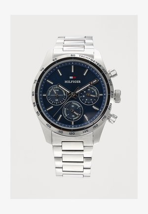 Montre-bracelet en métal argenté avec un cadran bleu foncé, trois sous-cadrans, une lunette tachymètre et des index et aiguilles argentés, de marque Hilfiger.