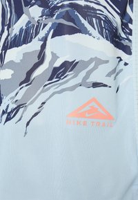 Camiseta Trail de Nike en azul claro con un gráfico de montaña en azul oscuro y gris. Presenta un triángulo de logo en rosa en la esquina inferior derecha.