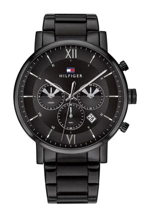 Sort Tommy Hilfiger armbåndsur med lænke i metal, romertal ved 12 og 6; tre subdialer og datovindue ved kl. 4.