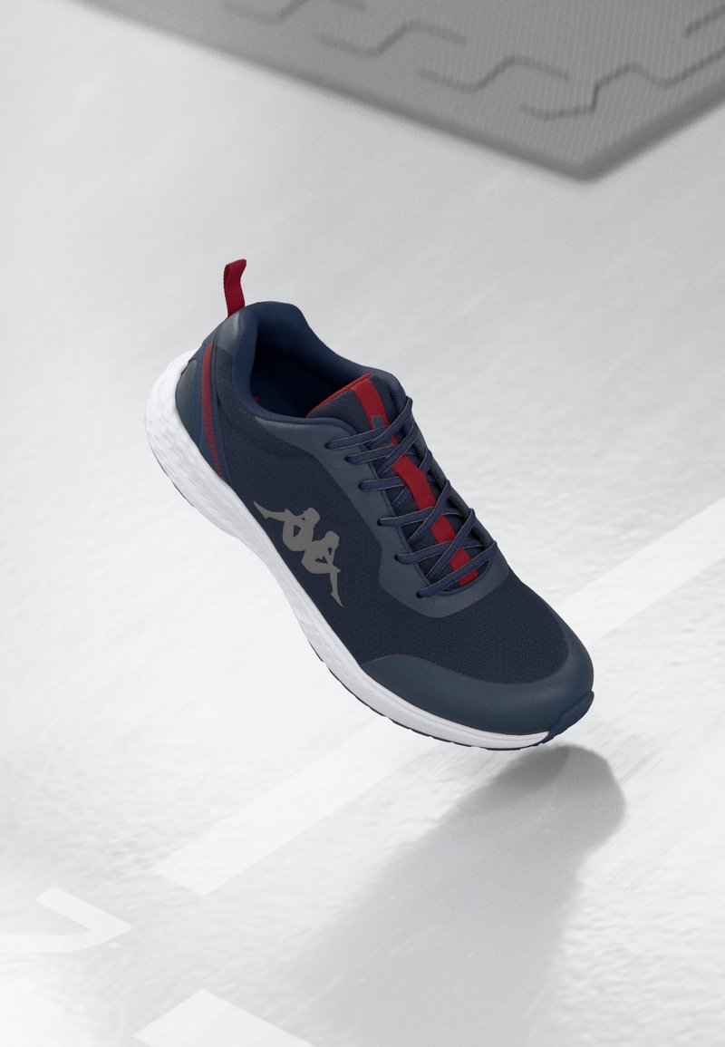Navy blue athletic shoe with a mesh upper, red accents, and a white textured sole. Features a logo on the side and a heel tab for easy wear.