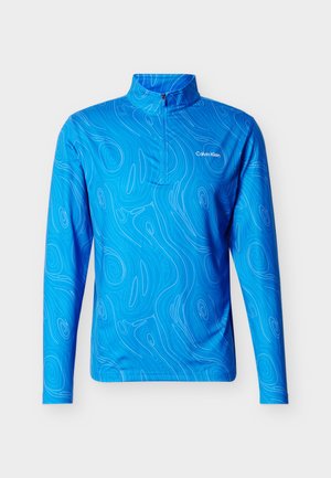 Élénk kék hosszú ujjú sportfelső finom hullámos vonalmintával, negyed cipzáras gallérral, és fehér Calvin Klein logóval a mellrészen.