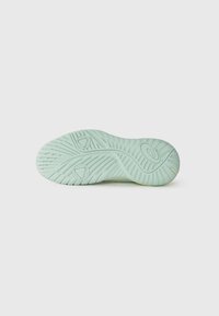 Semelle de sneaker vert clair avec un motif de traction texturé et des accents de logo. Le design présente des arêtes et des éléments circulaires pour une meilleure adhérence.
