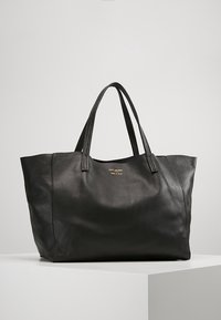 Svart läder tote-väska med en texturerad yta, två robusta handtag och subtil guldbranding på framsidan. Rektangulär form med öppen topp.